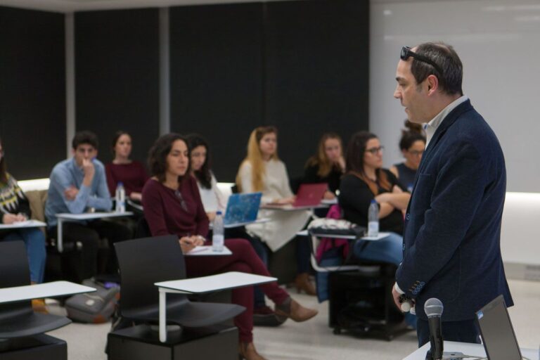 Luis está de perfil y de dirige a un auditorio joven.